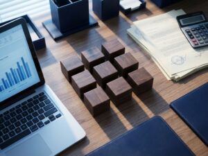 Bovenaanzicht van modern bureau met negen houten blokken in raster, laptop, juridische documenten en rekenmachine